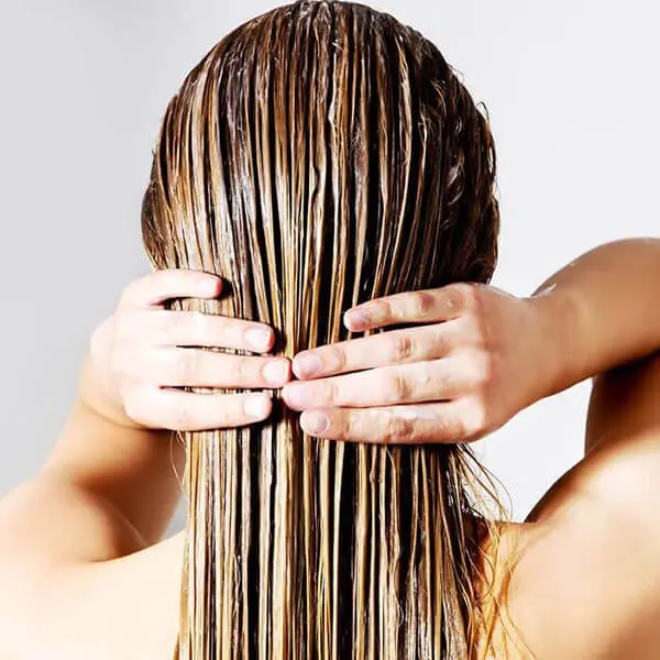 A woman on vacation is holding her hair with her hands.