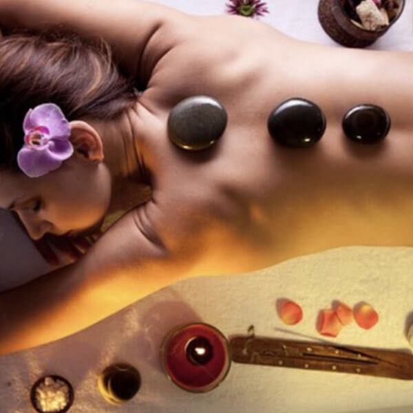 A woman enjoying a relaxing massage with hot stones as part of her vacation rental services.