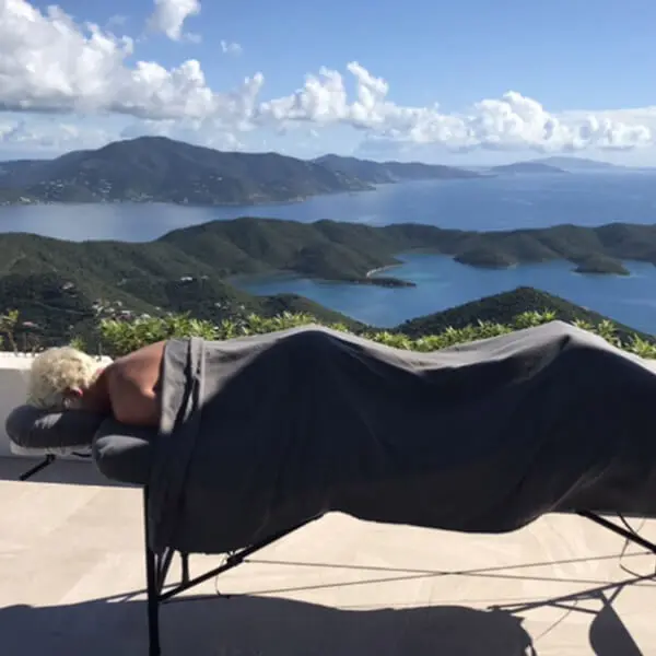 A woman enjoying a relaxing massage on a comfortable table overlooking the serene ocean view.